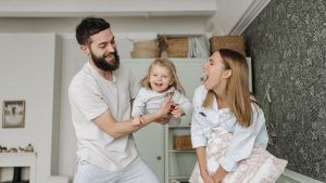 Joyful parents playing with their daughter at home, showcasing love and happiness.